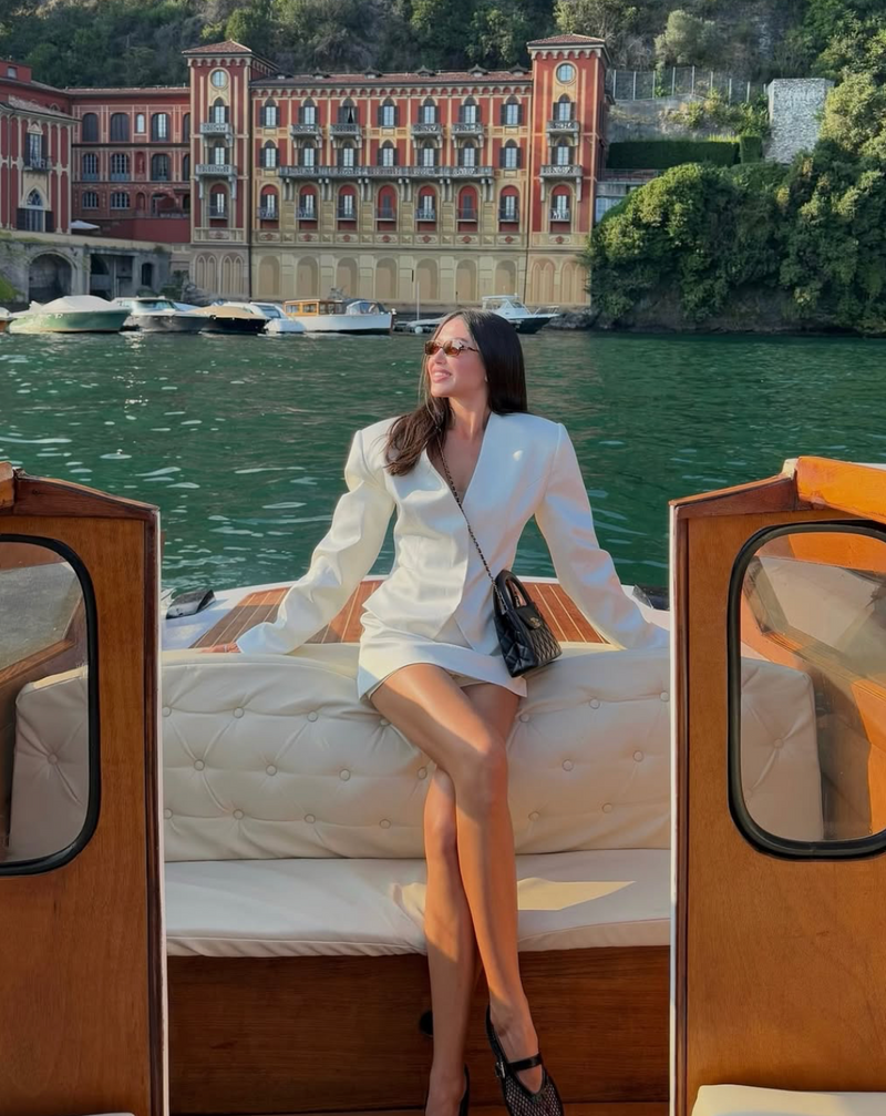 Woman in a white outfit sitting on a boat with a scenic background