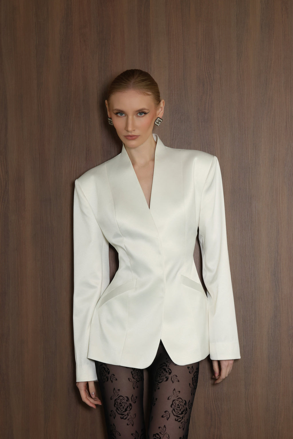 Woman wearing a white blazer against a wooden background