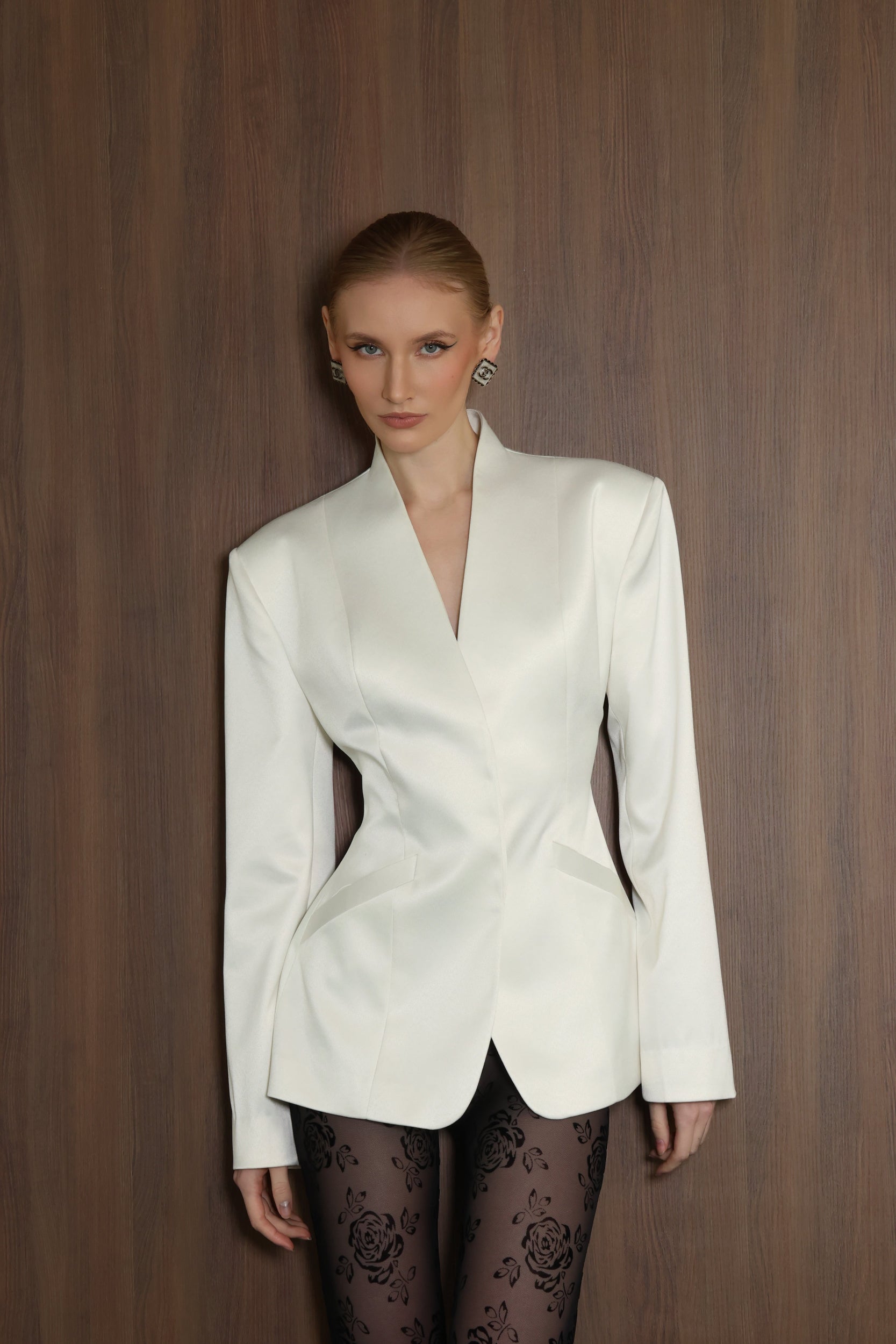 Woman wearing a white blazer against a wooden background