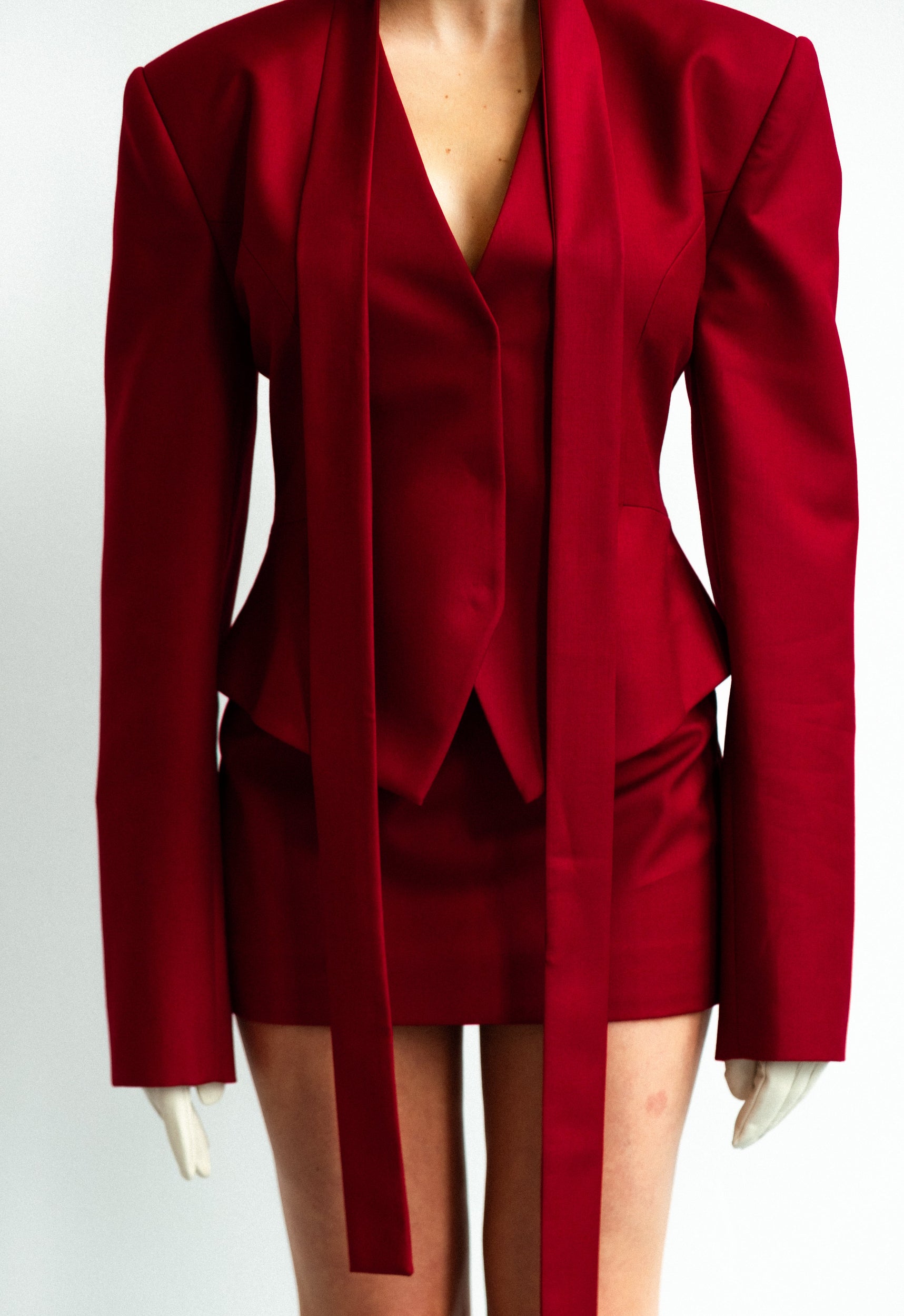 Red suit with a jacket and skirt on a mannequin against a white background