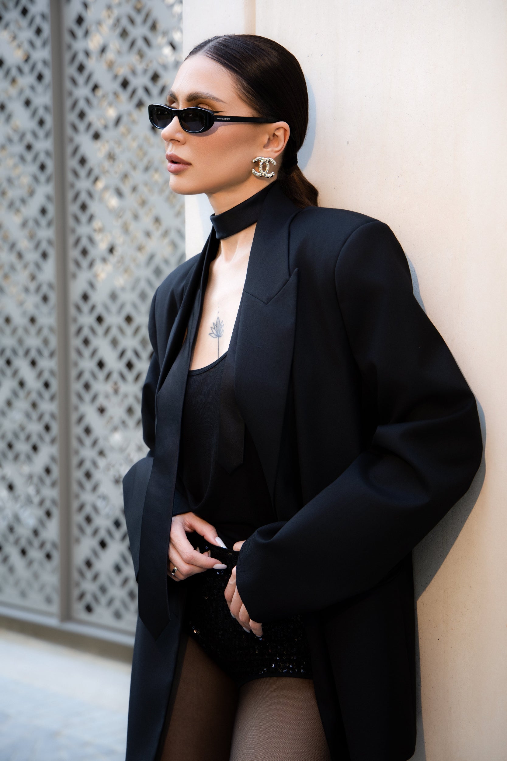 Woman in a black outfit leaning against a wall.